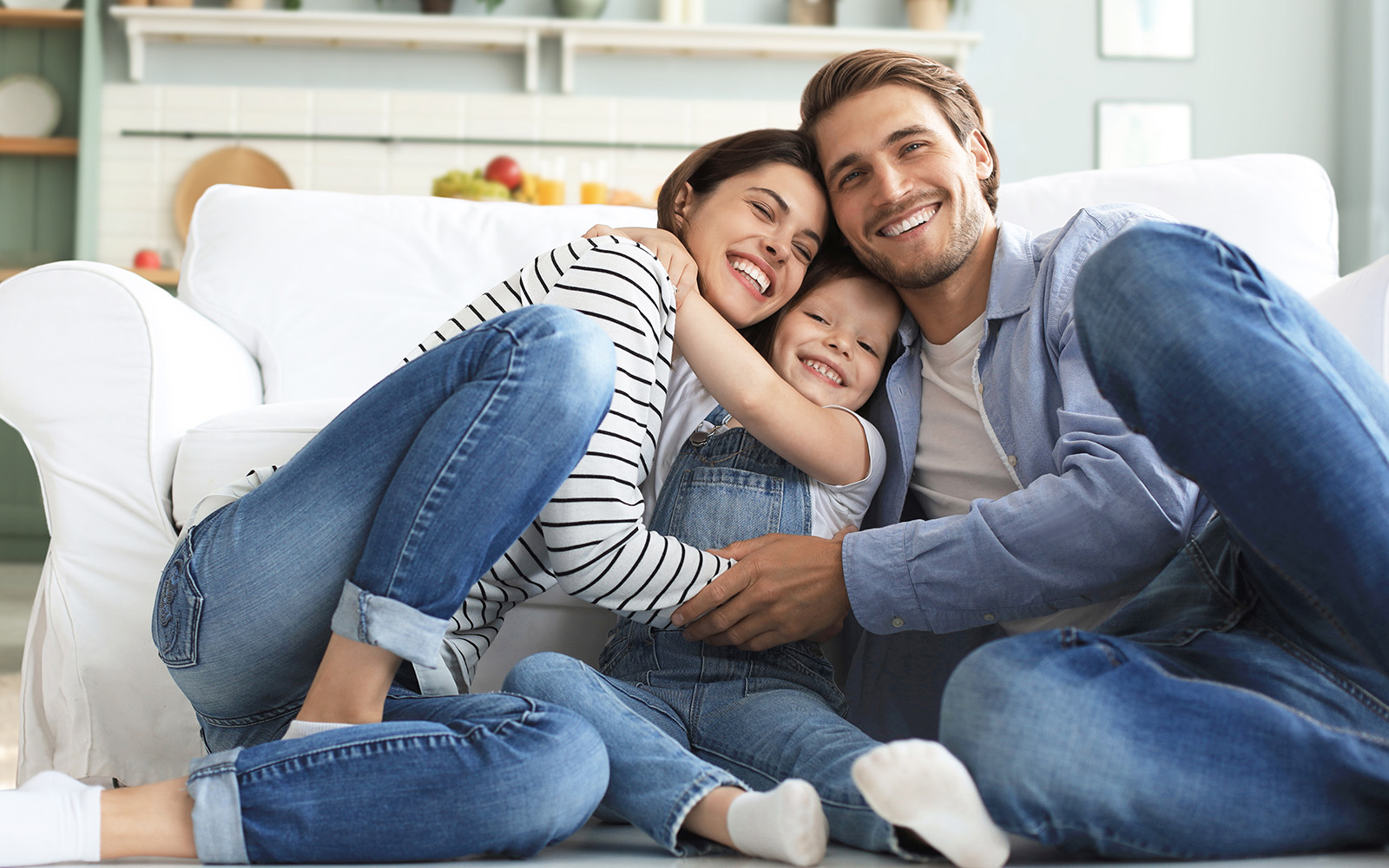 A family of four, including an adult couple and two children, sitting together on a couch with a warm and joyful atmosphere.