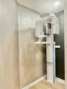 The image shows a modern dental office with a large, white MRI machine in the corner of the room.