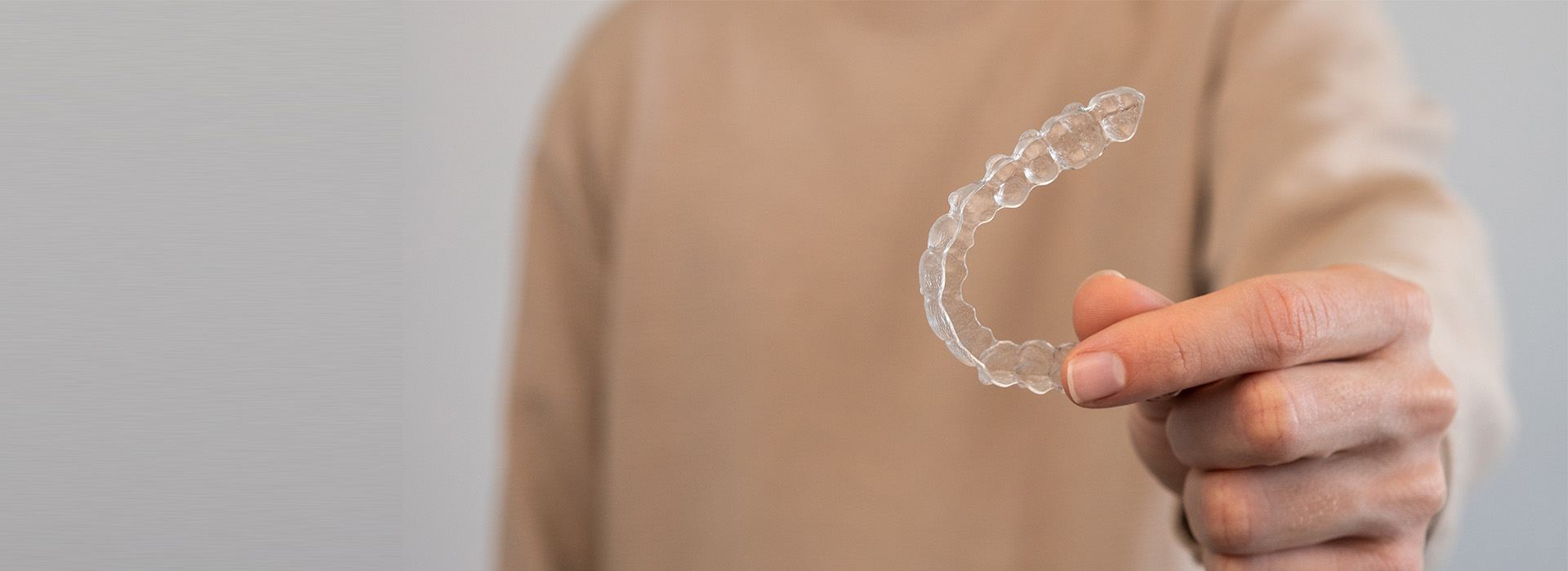 Hand holding a transparent bubble with a person s face inside, against a blurred background.