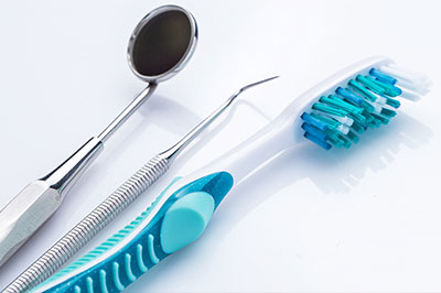 Dental instruments and a toothbrush on a white surface.