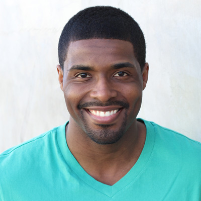 An elderly couple, a man and a woman, are smiling and embracing each other outdoors.