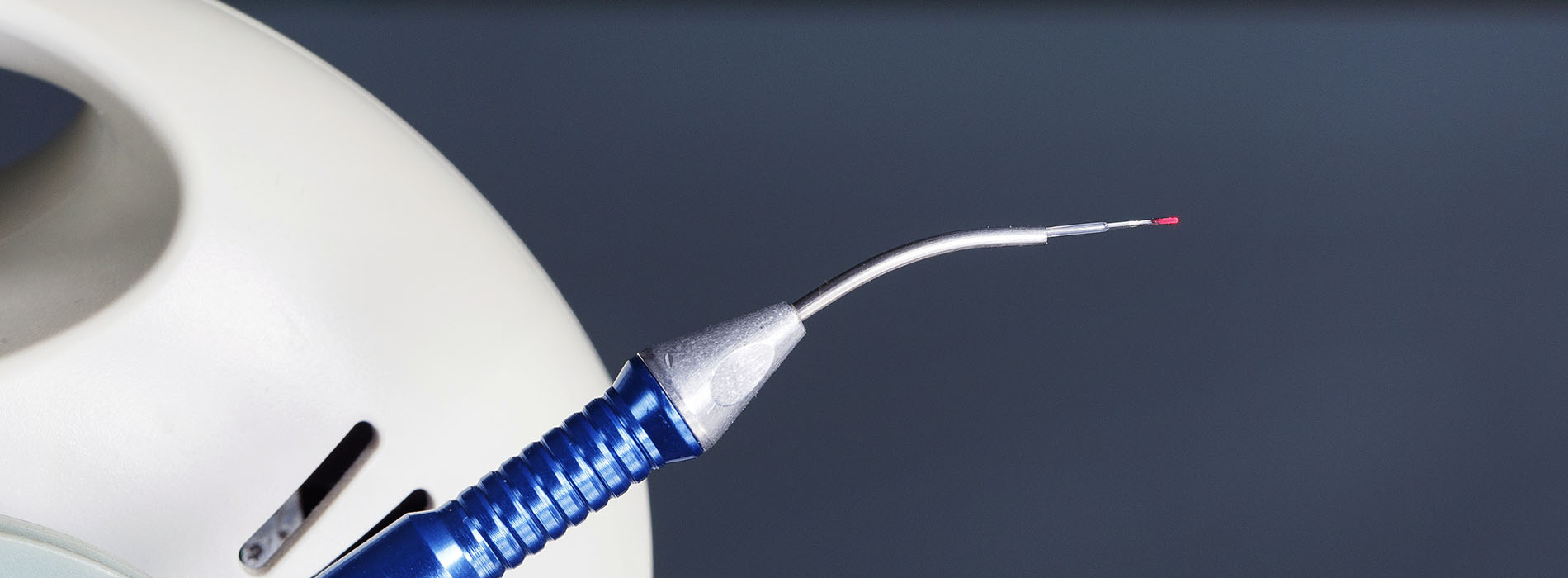 An image of a medical device with an attached syringe, showcasing its components against a dark background.