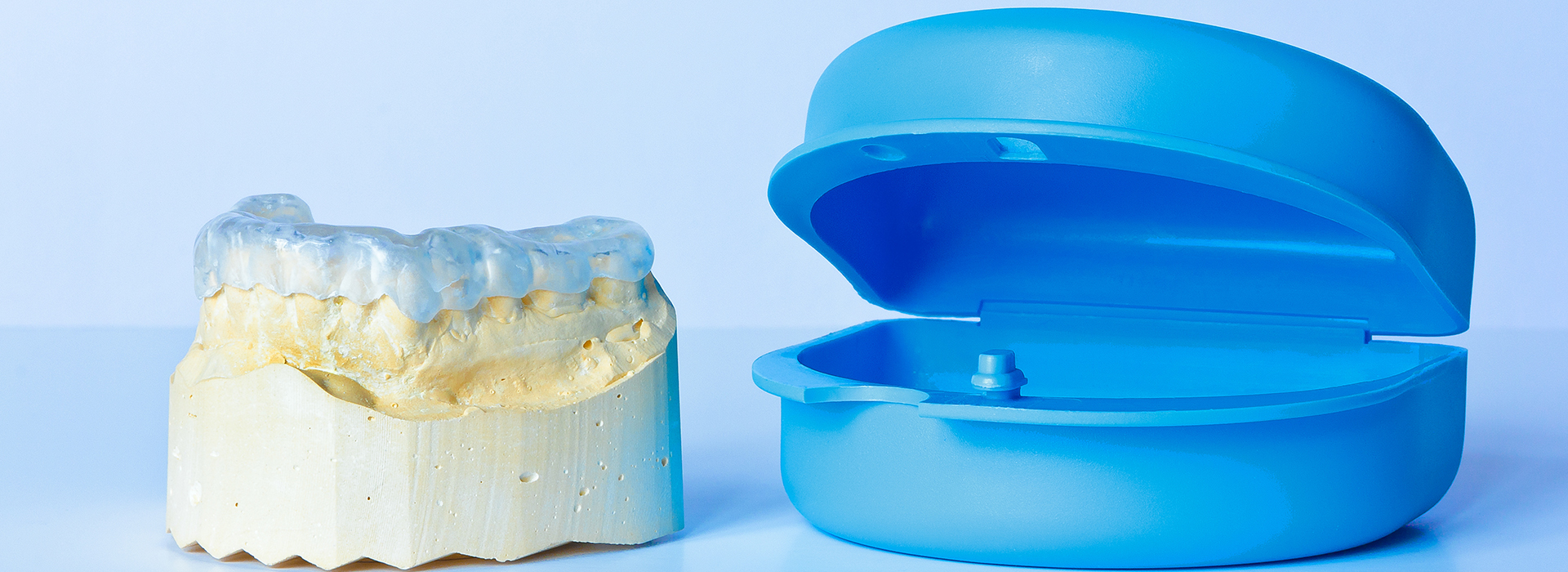 The image shows a blue dental crown and a yellow resin model of a tooth, both placed against a white background.