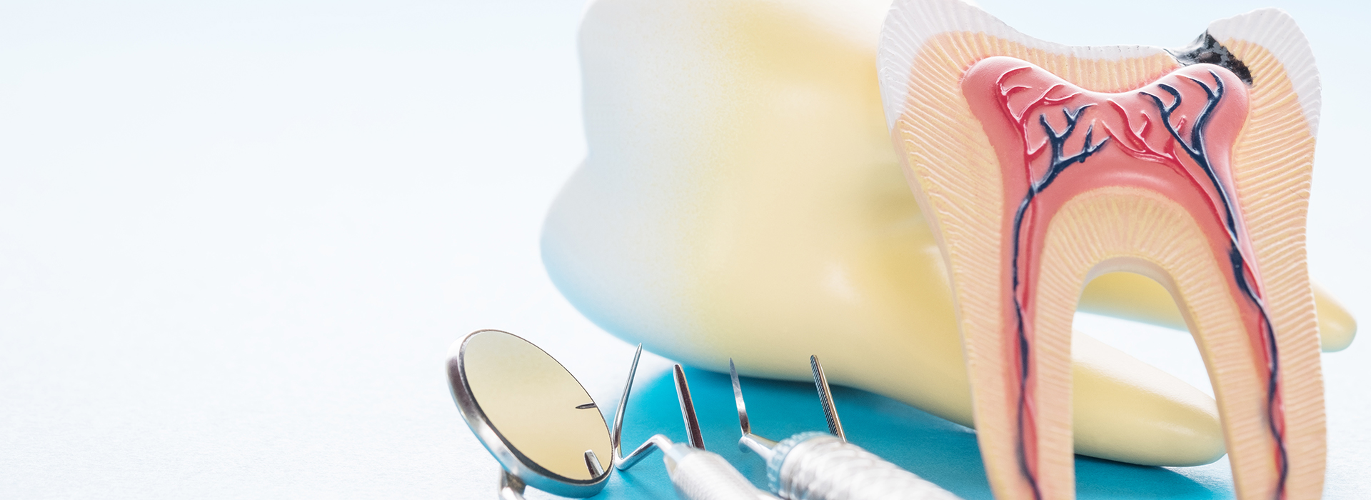 The image displays a dental model with an artificial tooth, placed on a blue background alongside a medical device that resembles a stethoscope.