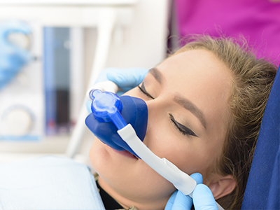 The image depicts a person receiving oxygen therapy using a medical device, with the assistance of a healthcare professional.